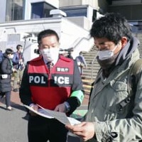 ガソリンを携行缶で購入する際の注意点が書かれたチラシを配る警視庁西新井署員＝27日午前、東京都足立区