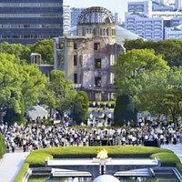 昨年8月6日、広島市の平和記念公園で黙とうする人たち。後方は原爆ドーム