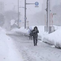 雪が降りしきる中、青森市内を歩く人＝12日午後2時22分