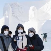 2020年2月の「さっぽろ雪まつり」に登場した大雪像前で、マスク姿で記念撮影する観光客＝札幌・大通公園