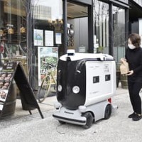 弁当を配達ロボットに入れる店員＝25日午前、東京・大手町