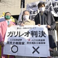 衆院選の「1票の格差」訴訟の判決を受け、東京高裁前で「ガリレオ判決」と書かれた紙を掲げる升永英俊弁護士（中央）ら＝2日午後