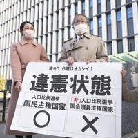 福岡高裁前で「違憲状態」と書かれた紙を掲げる原告側の升永英俊弁護士（右）ら＝21日午後