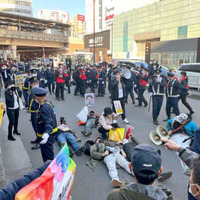 市民団体のデモを妨害しようとJR吉祥寺駅前の車道に寝そべる人たち＝2021年12月4日、東京都武蔵野市
