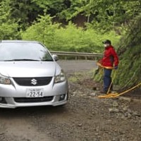 山梨県道志村の山中で、規制線の外に出る車両＝17日午後