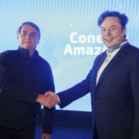 米電気自動車テスラのイーロン・マスクCEO（右）と握手するブラジルのボルソナロ大統領＝20日、ブラジル・ポルトフェリス（ブラジル通信省提供、AP＝共同）