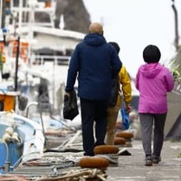 事故の現場海域周辺に行く船に向かう地元の小型観光船の運航関係者ら。花束を手にしていた＝23日午前、北海道斜里町