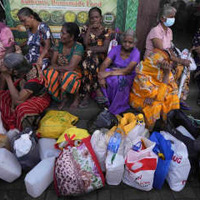 灯油を求めてガソリンスタンドの近くで座り込む女性たち＝26日、スリランカ・コロンボ（AP＝共同）
