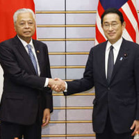 会談を前に握手するマレーシアのイスマイルサブリ首相（左）と岸田首相＝27日午後、首相官邸