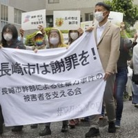 女性記者が性暴力被害を訴えた訴訟で、横断幕を手に長崎地裁に向かう原告側支援者ら＝30日午前