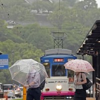 傘を差して熊本市内を歩く人たち。上は熊本城＝5日午前8時11分