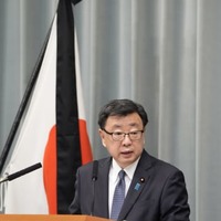 弔旗の前で記者会見する松野官房長官＝11日午前、首相官邸