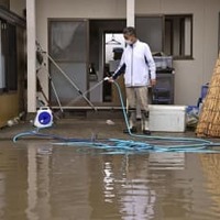 大雨の影響で浸水した自宅の掃除をする男性。家屋は床上1メートルまで水に漬かり、冷蔵庫やテレビなどの家電製品が壊れたという。「この7年で3回目の被害。堤防をしっかりと整備してほしい」と訴えた＝17日午前、宮城県大崎市