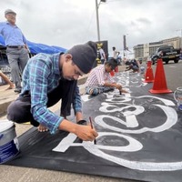 21日、スリランカ最大都市コロンボの大統領府近くで抗議の横断幕をつくる男性（共同）