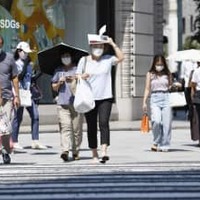 強い日差しの中、マスク姿で横断歩道を渡る人たち＝9日午後、東京都中央区