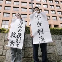 控訴審判決後に「不当判決」と書かれた紙を掲げる矢崎暁子弁護士（左）と堀江哲史弁護士＝26日午前、名古屋高裁前