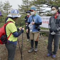 浅間山の黒斑コース登山口で、登山者（左側）に安全な登山を呼びかける「山びこの会」のメンバーら＝4日午前