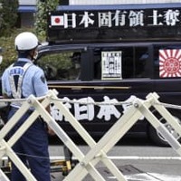 展示の中止を求める街宣車と警戒に当たる兵庫県警の警察官＝10日午後、神戸市