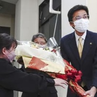 当選が決まり、事務所で花束を受け取る斉藤栄氏（右）＝11日夜、静岡県熱海市