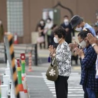 安倍元首相銃撃事件の現場付近で手を合わせる人たち＝27日午後1時21分、奈良市