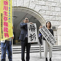 生活保護費減額処分の取り消しなどを求めた訴訟の判決後、「勝訴」と書かれた紙を掲げる弁護士ら＝19日午前、横浜地裁前