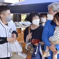 1日限定で復活した福島県大熊町のキウイ直売所で、訪れた人と話す関本元樹さん（左端）＝3日午後