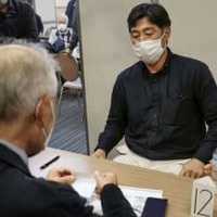 東京都内で開かれた相談会で、アドバイスを受ける参加者（奥）＝26日午後