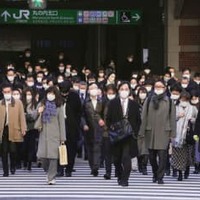 仕事始めを迎え、マスク姿で通勤する人たち＝4日午前、JR東京駅前