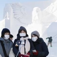 2020年2月の「さっぽろ雪まつり」に登場した大雪像前で、マスク姿で記念撮影する観光客＝札幌・大通公園