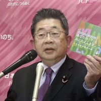 記者会見で新たに作成したリーフレットを手に説明する共産党の小池書記局長＝2日午後、国会