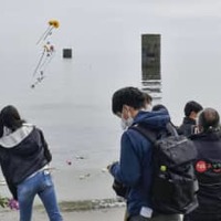 事故の追悼式で、砂浜から海へ献花する参加者＝12日午後、山口県宇部市