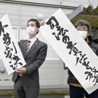 生活保護費の基準額引き下げを巡る訴訟の判決を受け、「不当判決」などと書かれた紙を掲げる弁護士ら＝7日午後、秋田地裁前