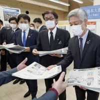 震災写真展で新聞を配る（右から）福島民報社の芳見弘一社長、岩手日報社の東根千万億社長、東京新聞の菅沼堅吾代表＝11日午前、東京都品川区