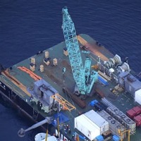海面上につり上げられ、作業船「海進」に横付けされた観光船「KAZU　1」（左下）＝26日午後6時57分、北海道斜里町沖（共同通信社ヘリから）