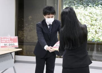 法務省の鷦鷯昌二参事官（奥）に署名を手渡す小関代里子さん＝22日午後、東京都千代田区