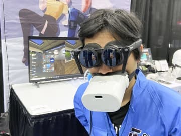 仮想現実（VR）対応端末を装着して来場者に説明するパナソニックの子会社シフトールの岩佐琢磨CEO＝3日、米ラスベガス（共同）