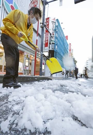 まとまった積雪から一夜明け、道路の除雪作業をする人たち＝7日午前、東京・新橋