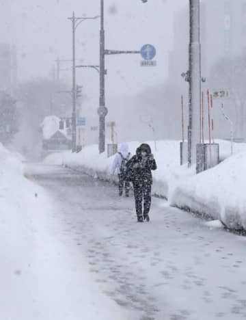 雪が降りしきる中、青森市内を歩く人＝12日午後2時22分