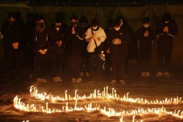 兵庫県伊丹市の昆陽池公園で行われた阪神大震災の追悼集会で、手を合わせる人たち＝16日午後5時46分