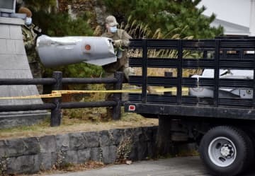 米軍三沢基地のF16戦闘機が投棄した燃料タンクの一部を落下現場から回収する米軍関係者＝2021年12月、青森県深浦町