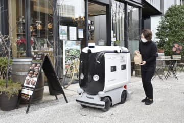 弁当を配達ロボットに入れる店員＝25日午前、東京・大手町