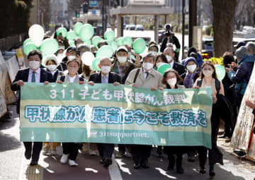 原発事故による被ばくで甲状腺がんを発病したとして、東電に賠償を求め提訴に向かう原告弁護団ら＝27日午後、東京地裁前