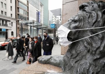 東京・銀座をマスク姿で歩く人たち。百貨店前のライオン像もマスクを着けられていた＝30日午後