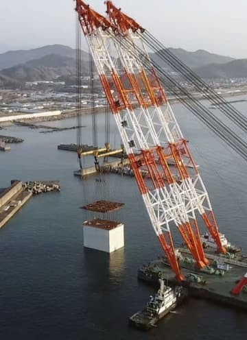 大型クレーン船でつり上げられる巨大ケーソン＝2日午前、高知港（四国地方整備局高知港湾・空港整備事務所提供）