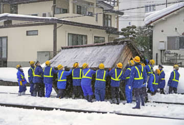 線路に滑り落ちた小屋を撤去する作業員ら＝3日午後4時40分ごろ、山形市