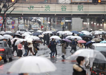 雪が降る中、東京・渋谷を歩く人たち＝10日午後