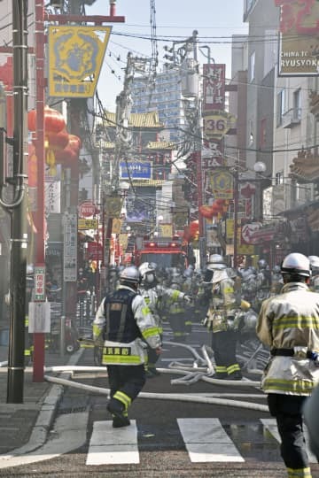 横浜中華街の火災現場付近で、消火活動をする消防隊員ら＝11日午前11時24分、横浜市