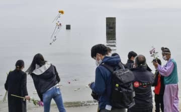 事故の追悼式で、砂浜から海へ献花する参加者＝12日午後、山口県宇部市