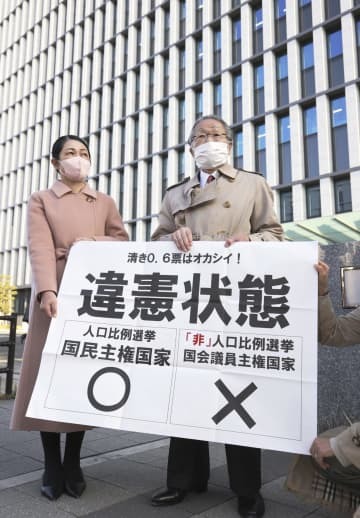 福岡高裁前で「違憲状態」と書かれた紙を掲げる原告側の升永英俊弁護士（右）ら＝21日午後