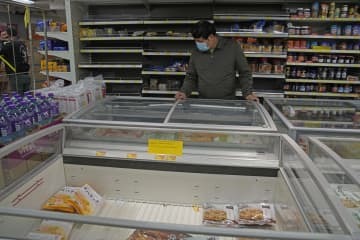 食料不足を懸念する住民が買いだめをする中、冷凍食品を探す男性＝5日、香港のスーパー（AP＝共同）